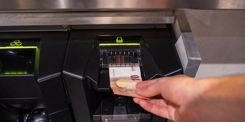 client insérant un billet dans un monnayeur automatique